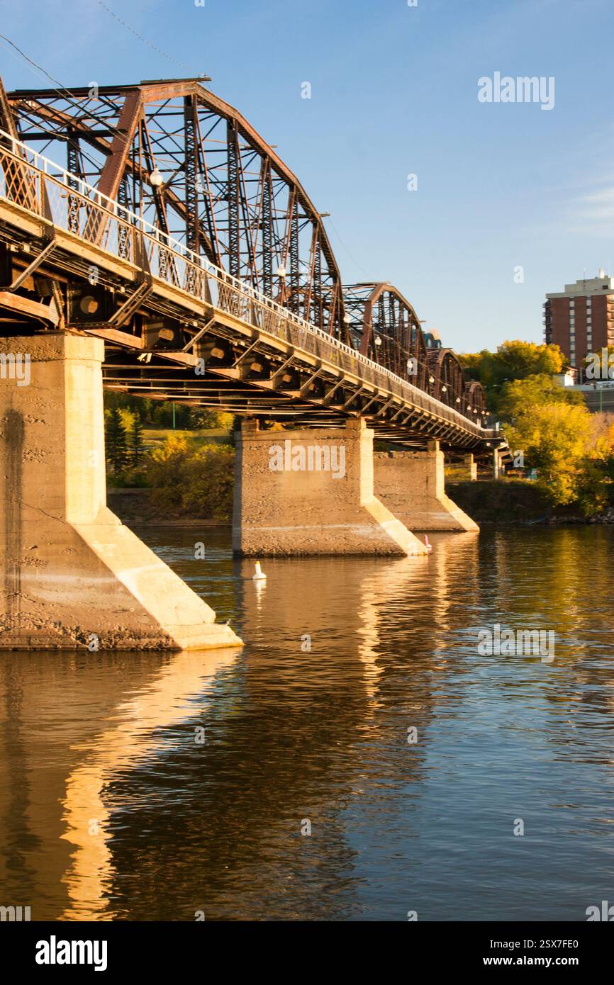 Il ponte attraversa un fiume con un riflesso del ponte nell'acqua. Il ponte è vecchio e ha un aspetto rustico Foto Stock