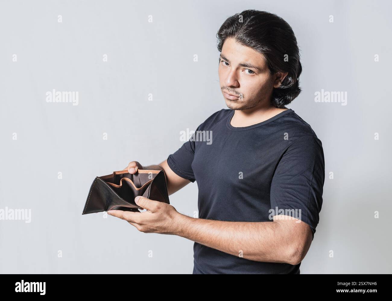 Persona in bancarotta che mostra un portafoglio vuoto isolato. Giovane infelice con crisi finanziaria Foto Stock