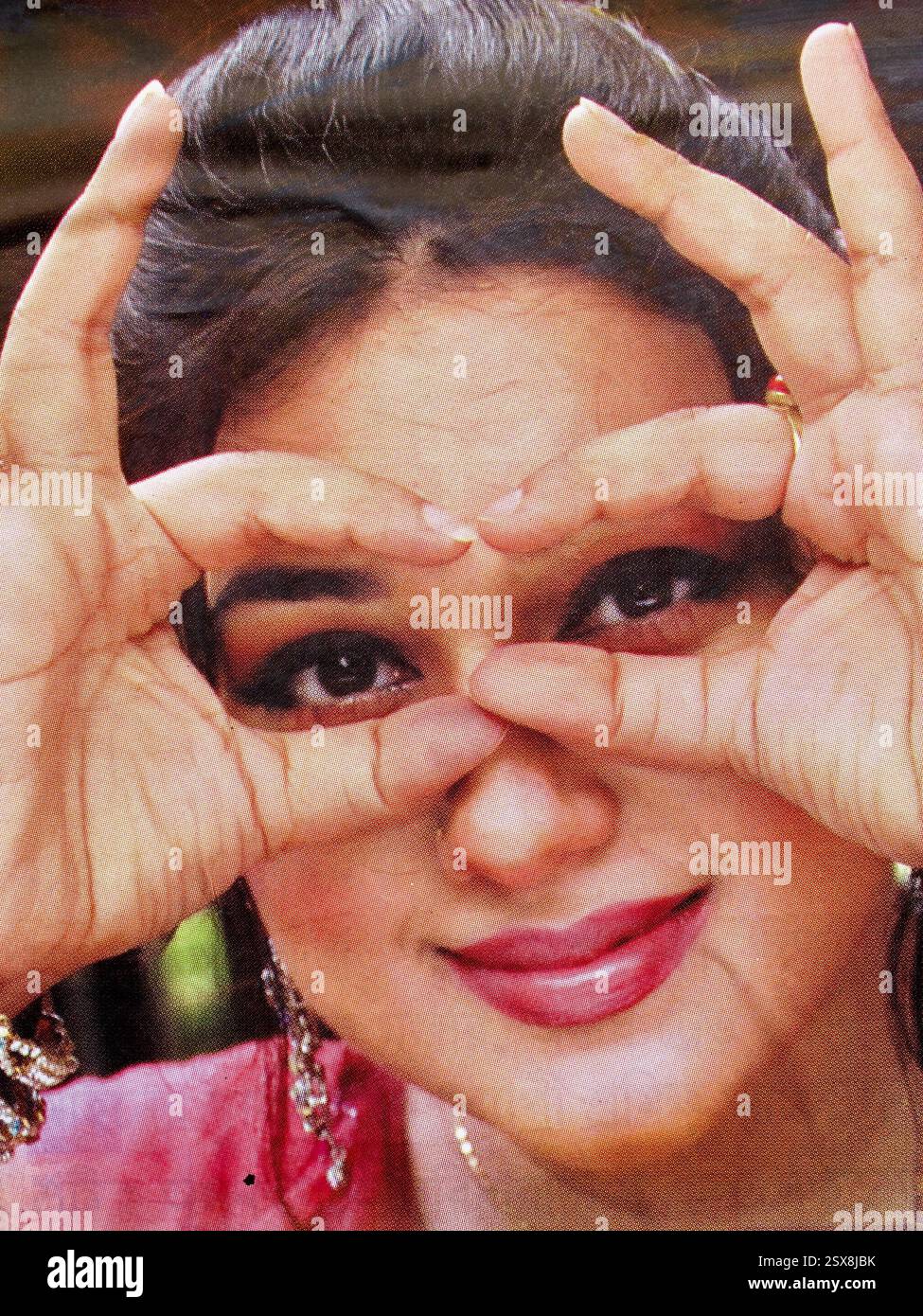 Poster cinematografico di Dhallywood a Dacca, Bangladesh, con una donna sorridente che inquadra scherzosamente gli occhi con le dita in uno scatto ravvicinato. Foto Stock