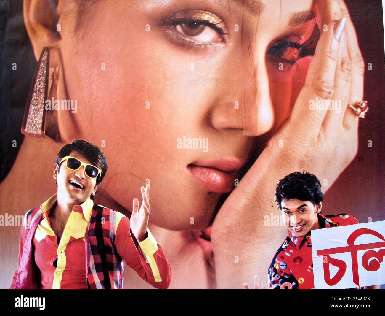 Poster cinematografico di Dhallywood a Dacca, Bangladesh, con un affascinante primo piano di una donna con due uomini allegri in abiti colorati. Foto Stock