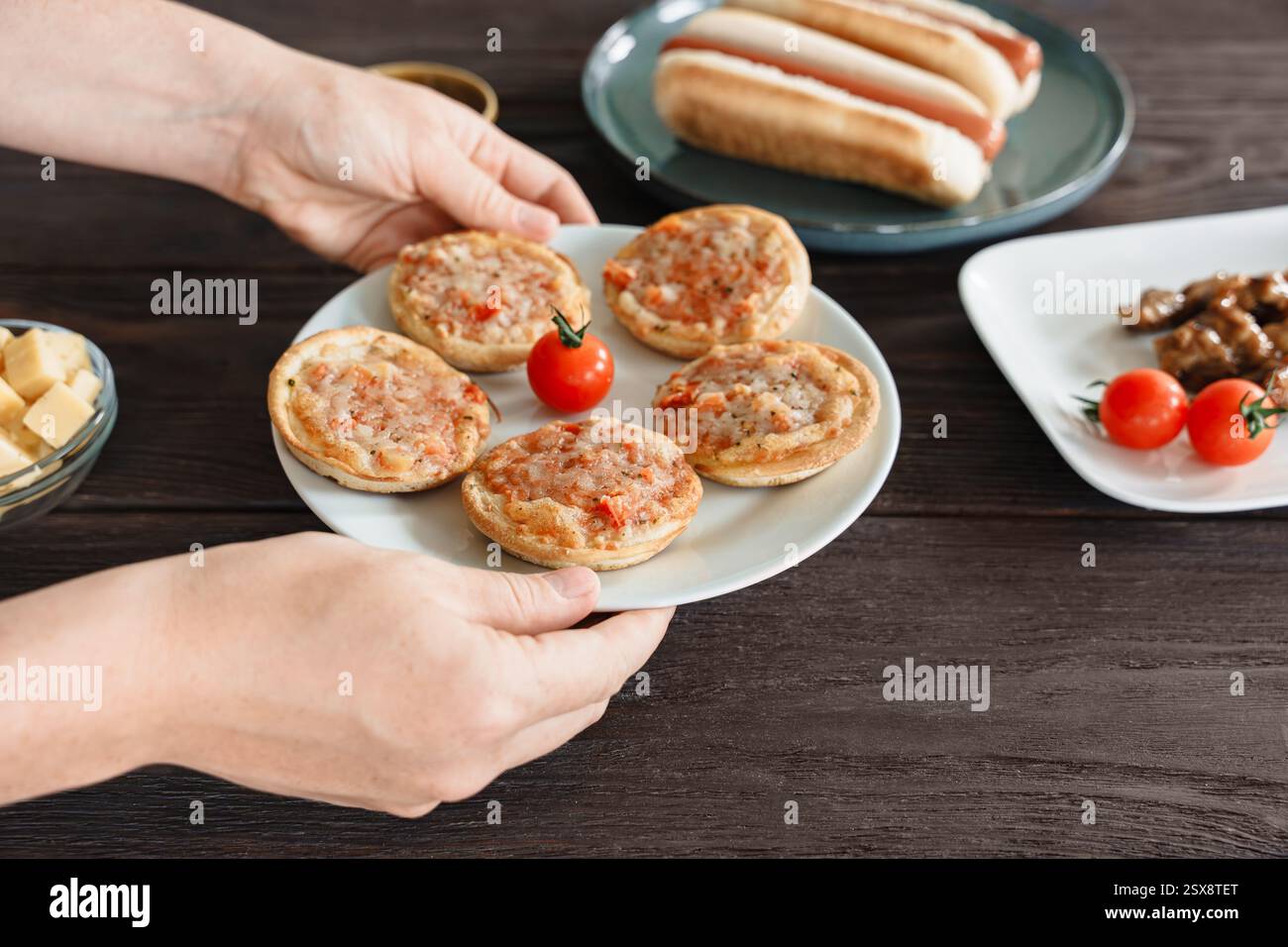 Un piatto con mini pizze al forno è condiviso a un tavolo con altri spuntini da bar per cene sociali Foto Stock