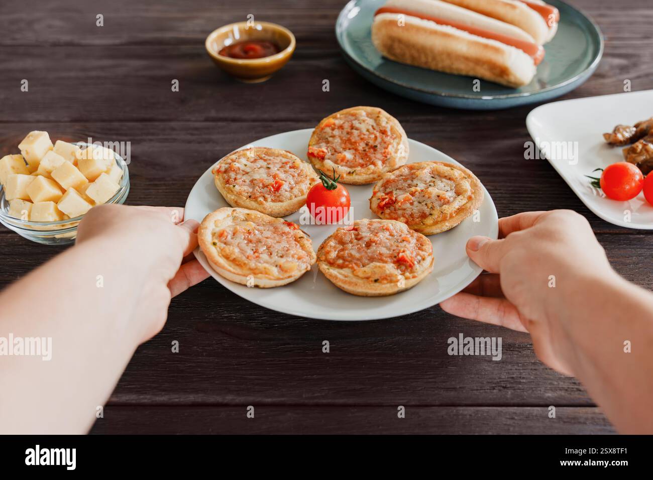 Mani che tengono in mano un piatto di pizze appena sfornate, fast food per feste o spuntini da bar Foto Stock