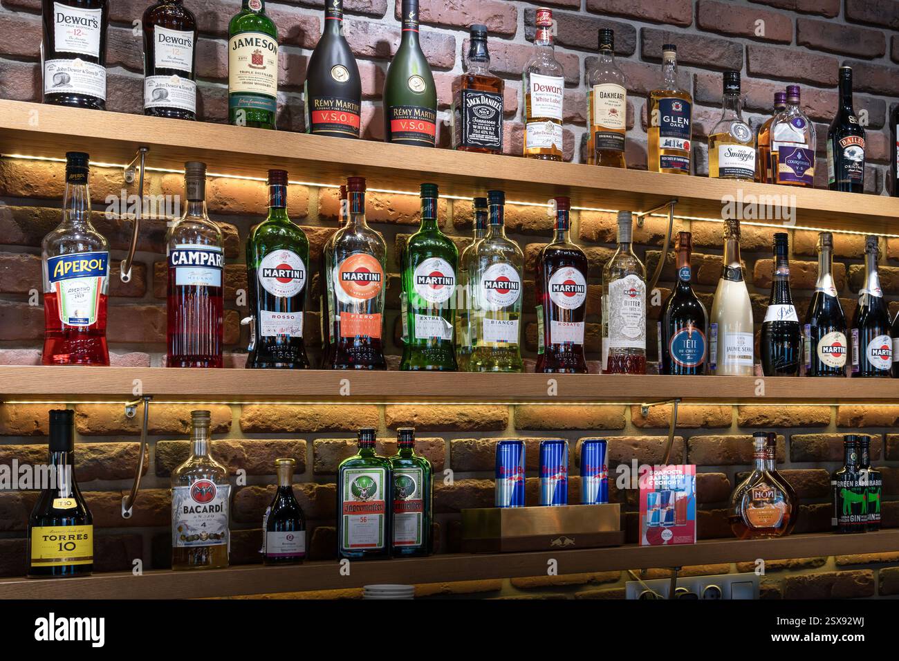 Martini e altri alcolici in mostra contro il muro di mattoni del loft. Tailandia, Phuket 12 gennaio 2025 : Un ben rifornito scaffale con un assortimento Foto Stock