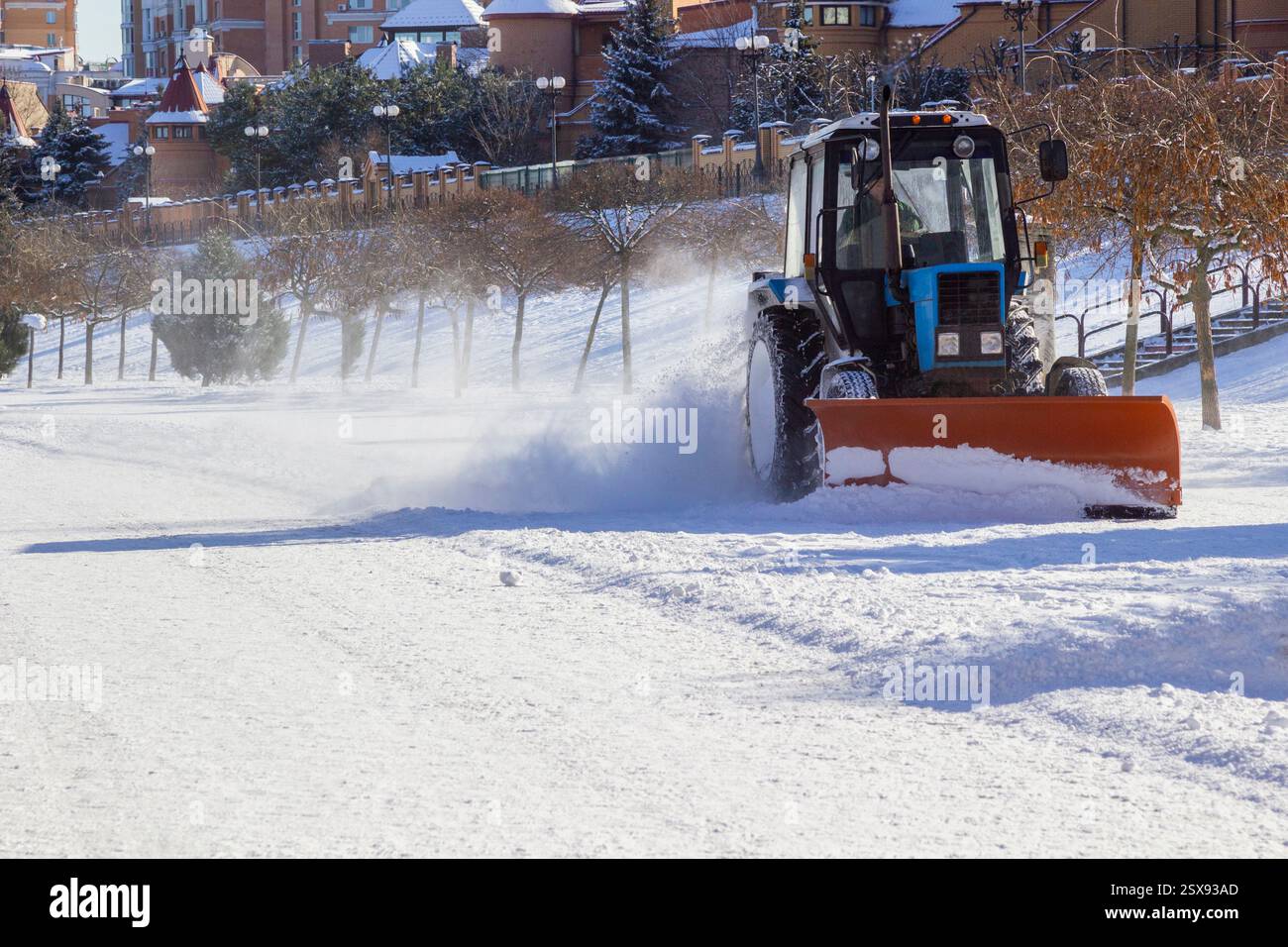 La macchina per la rimozione della neve sgombra la strada in una città di villeggiatura dopo una forte nevicata. Pulizia della neve. Foto Stock