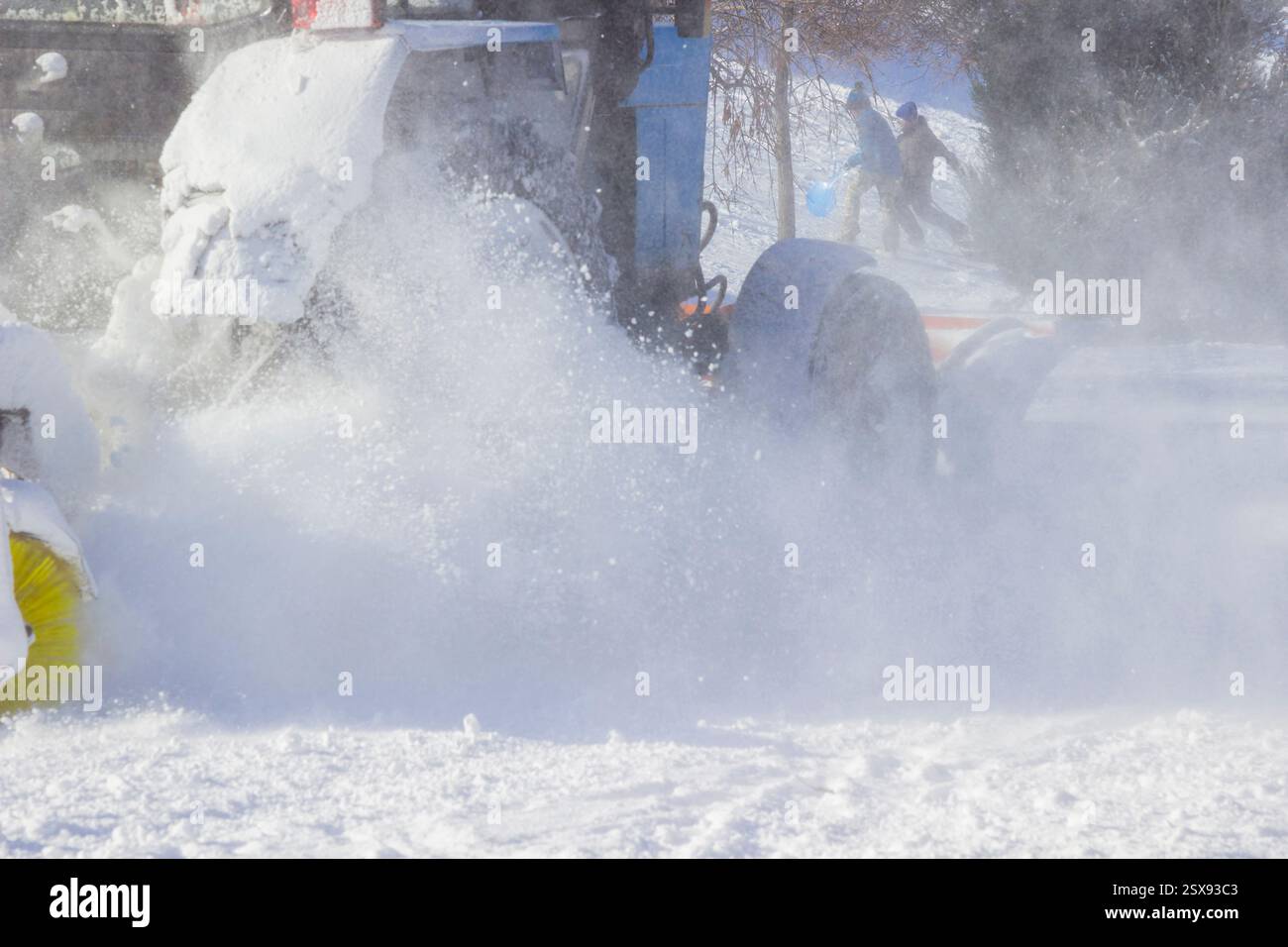 I bambini corrono sulla neve. Macchina per la rimozione della neve pulizia della strada dalla neve durante la tormenta in inverno. Parte del telaio Foto Stock