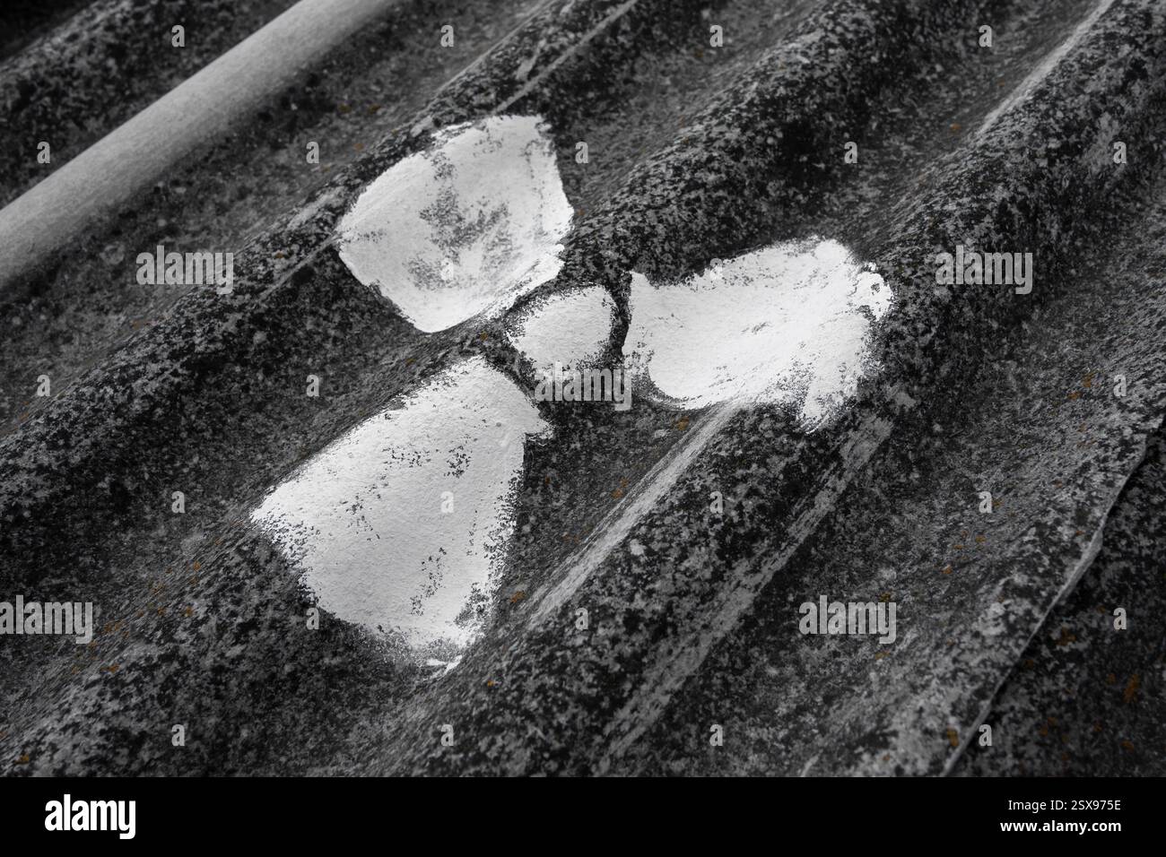 Simbolo radioattivo macchiato di vernice bianca su lastre di amianto ondulato, primo piano astratto e morbido Foto Stock