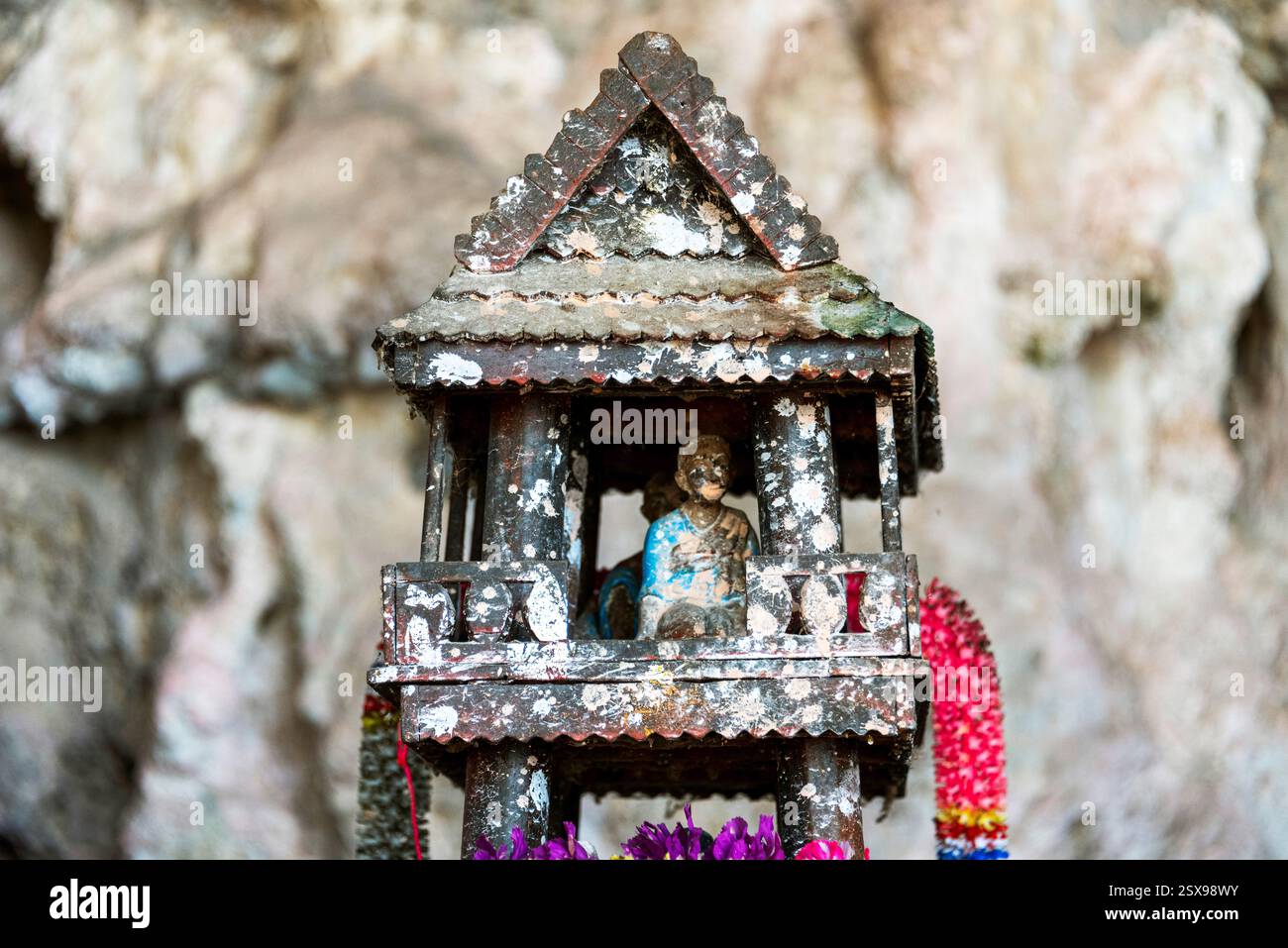 Piccolo santuario della casa degli spiriti all'interno di una grotta in Thailandia, utilizzato per offerte e preghiere religiose, che rappresenta la spiritualità locale e le antiche tradizioni Foto Stock