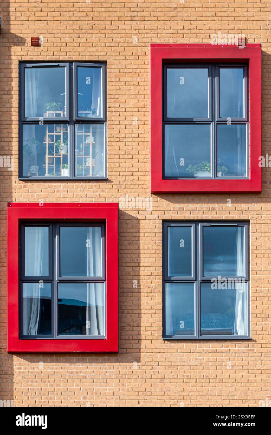 Nuovo edificio, blocco di appartamenti o appartamenti con inusuali cornici o dintorni di colore rosso brillante, Bordon, Hampshire, Inghilterra, Regno Unito. Architettura moderna Foto Stock
