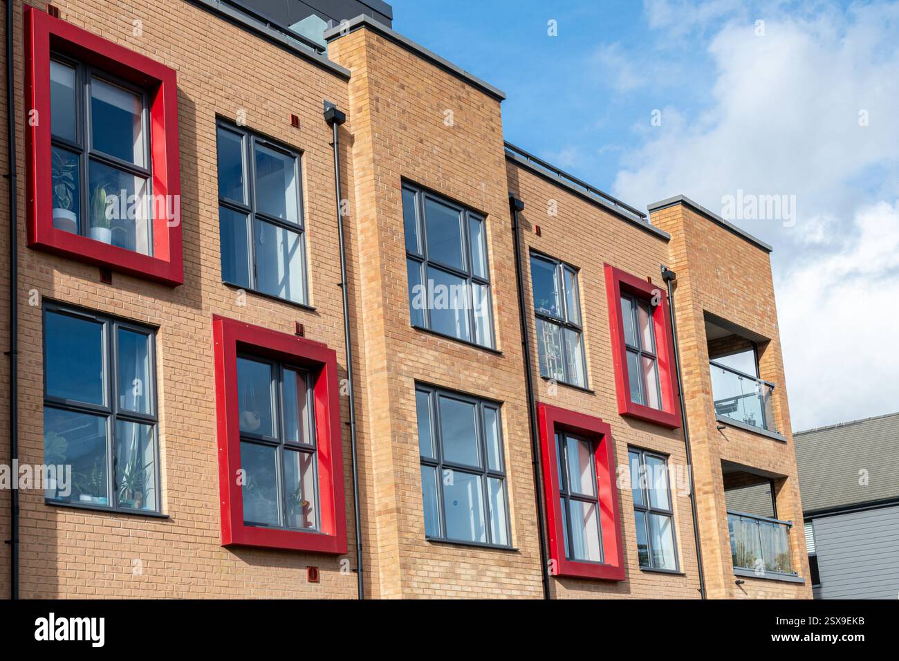 Nuovo edificio, blocco di appartamenti o appartamenti con inusuali cornici o dintorni di colore rosso brillante, Bordon, Hampshire, Inghilterra, Regno Unito. Architettura moderna Foto Stock