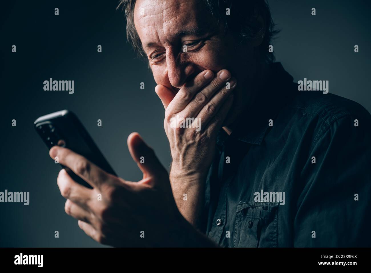 Uomo d'affari sorpreso che leggesse messaggi di testo sul cellulare, attenzione selettiva Foto Stock