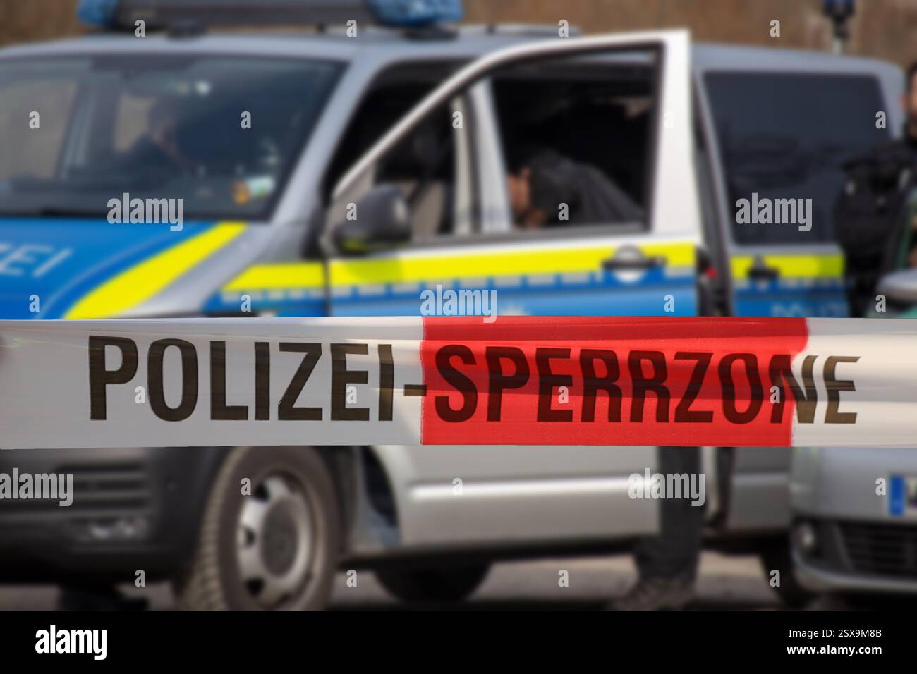 (Fotomontaggio) immagine simbolo di un'operazione di polizia: Nastro barriera con la scritta POLIZEI SPERRZONE davanti a un veicolo di emergenza Foto Stock (Fotomontaggio) immagine simbolo di un'operazione di polizia: Nastro barriera con la scritta POLIZEI SPERRZONE davanti a un veicolo di emergenza Foto Stock