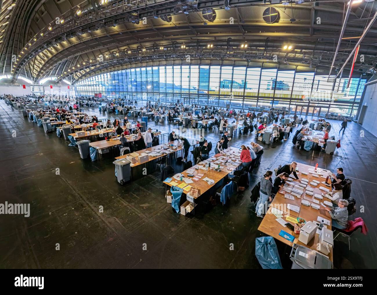 23 febbraio 2025, Assia, Francoforte sul meno: Gli assistenti elettorali lavorano a vari tavoli nel centro di voto postale del centro fieristico, distribuito tra i distretti elettorali postali. Si preparano nel centro di votazione postale nella sala esposizioni 3,1. per il prossimo conteggio delle votazioni dalle 17:6,00. Foto: Andreas Arnold/dpa Foto Stock