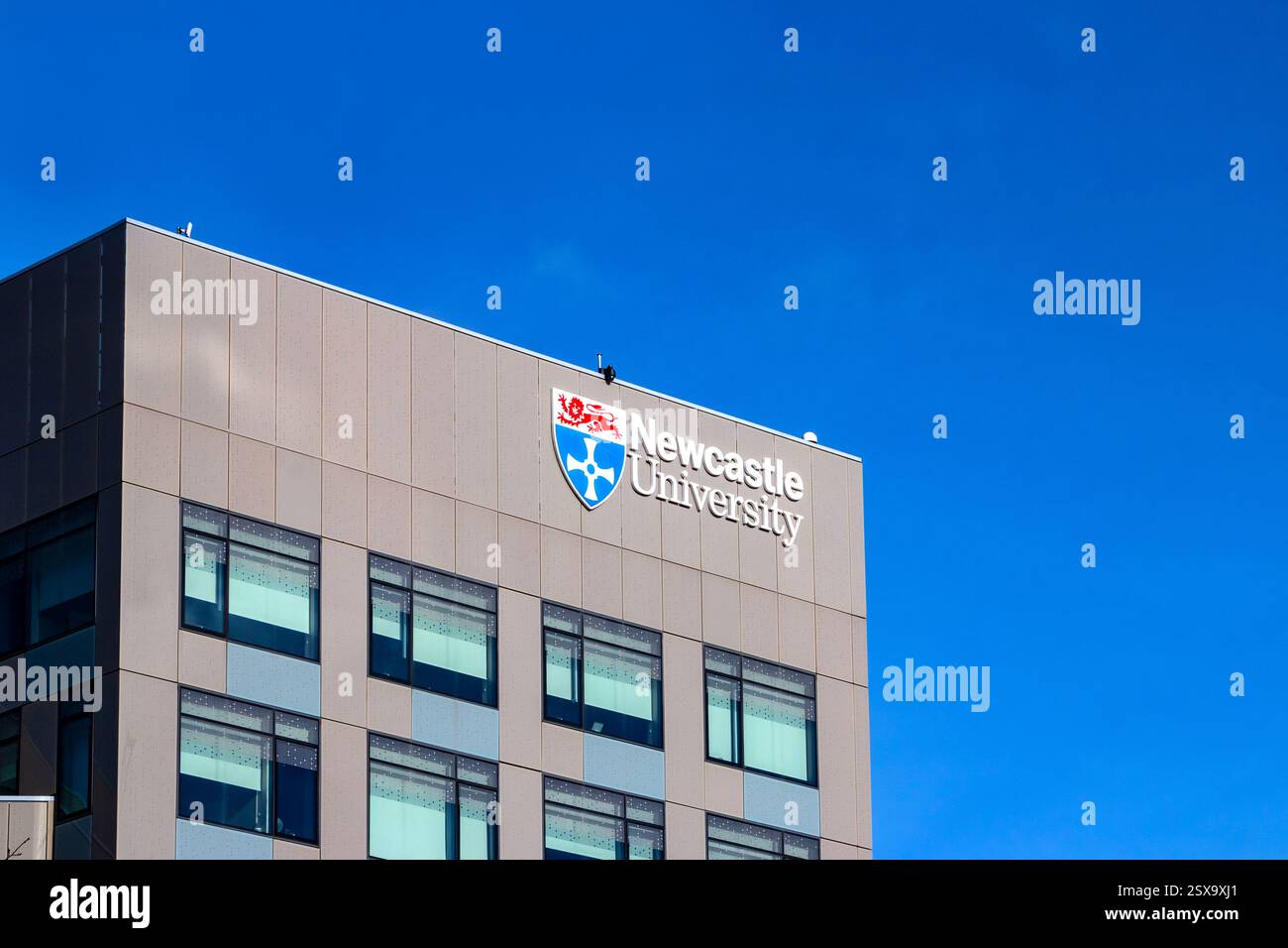 Moderna vista esterna dell'edificio delle scienze urbane della Newcastle University con il suo logo di spicco su un cielo azzurro Foto Stock