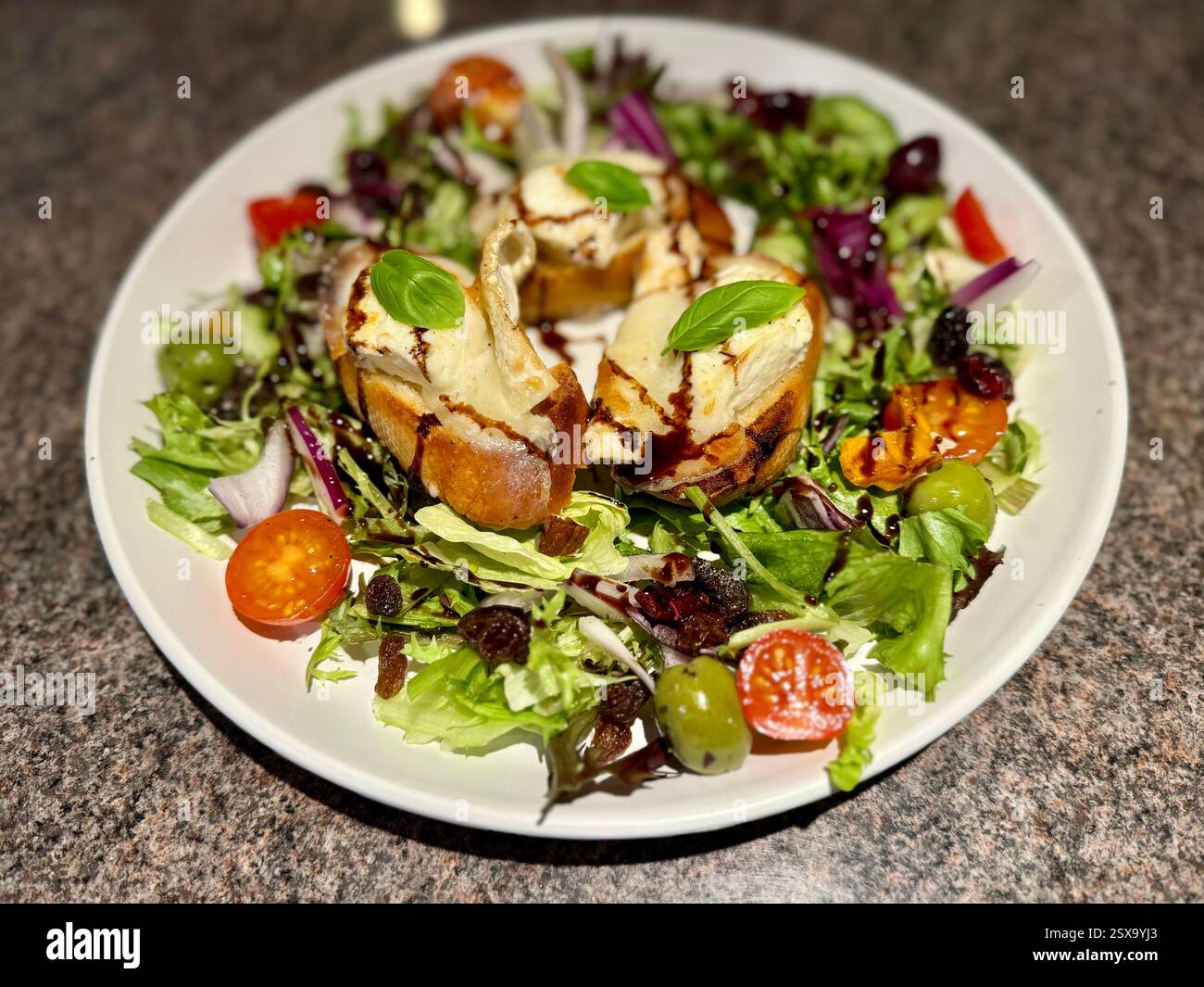Insalata di formaggio di capra spagnola con glassa balsamica, uvetta, noci, pomodori, insalata e olive Foto Stock