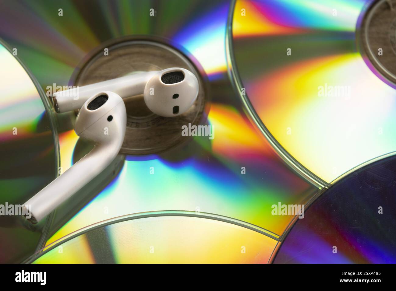 rifiniture colorate sui vecchi compact disc con due cuffie wireless sulla parte superiore Foto Stock