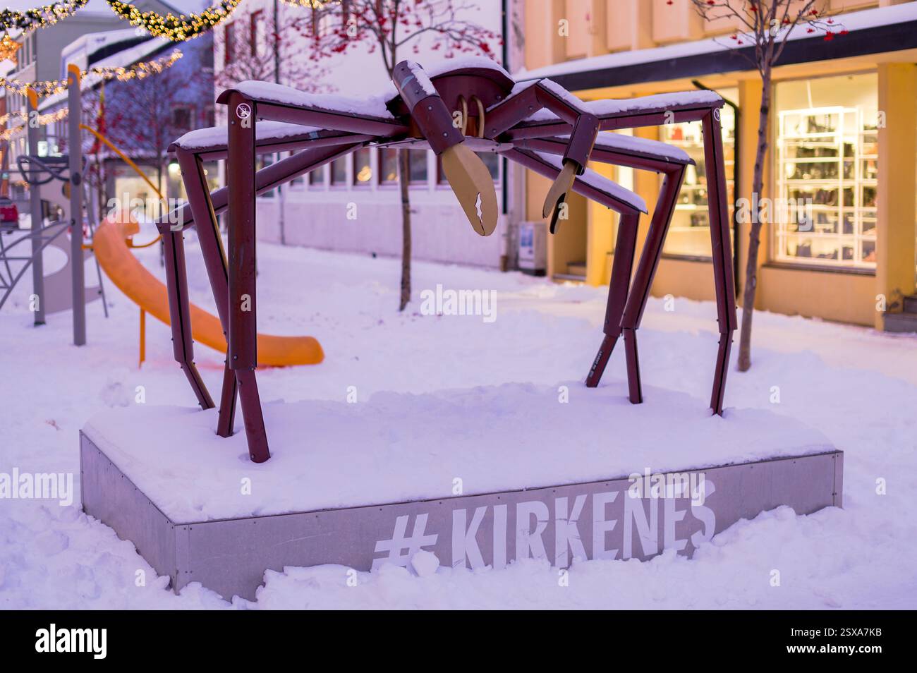 Ammira una delle strade pedonali di Kirkenes, con negozi che la fiancheggiano, una scultura di granchio reale è in primo piano, la Norvegia Foto Stock