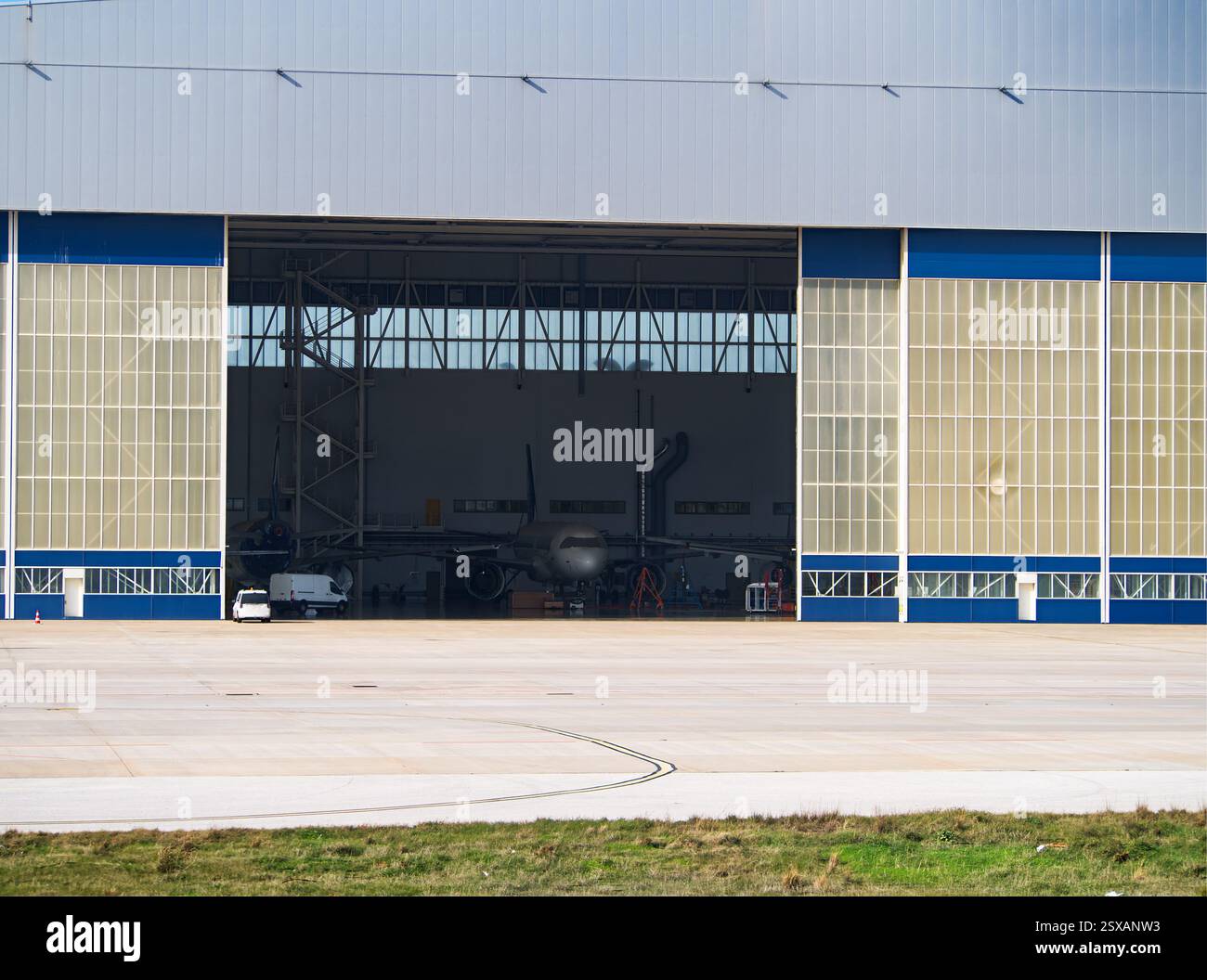 Grande hangar per aerei con esterno blu e bianco, porte aperte che rivelano l'aereo all'interno Foto Stock