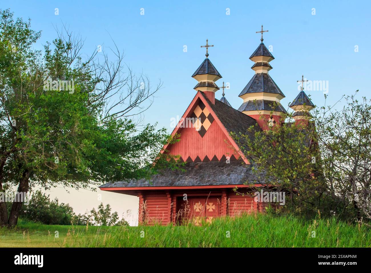Edificio rosso con una croce in cima. L'edificio è circondato da alberi Foto Stock