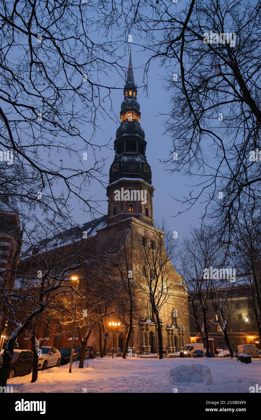 Chiesa di San Pietro a riga, in Lettonia, in una serata invernale nevosa. La storica chiesa gotica, originariamente costruita nel XIII secolo, presenta un'illuminazione Foto Stock