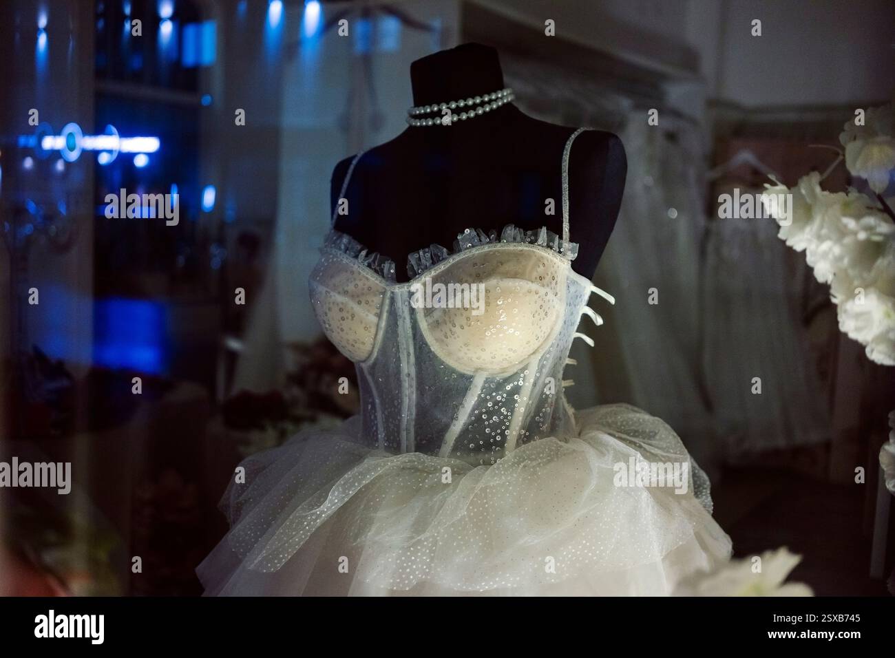 Vetrina di un salone di abiti da sposa, moderno abito da sposa bianco su un manichino nero. Foto Stock