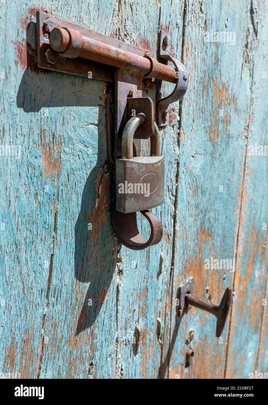Chiusura di un bullone di ferro con lucchetto su una vecchia porta di legno. Foto Stock