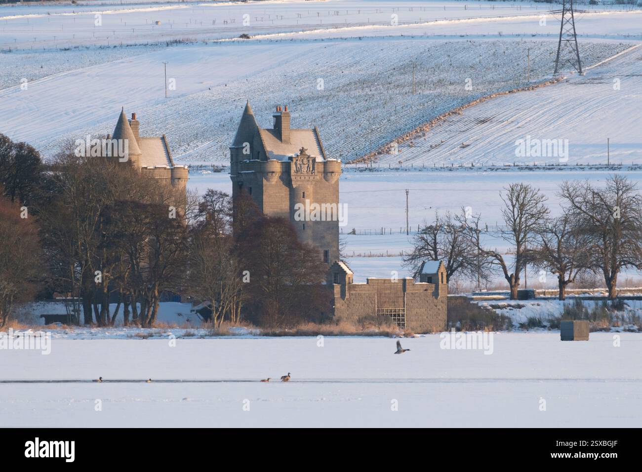 Le Gatehouse Towers a Dunecht Estate accanto al lago ghiacciato e coperto di neve di Skene in inverno Foto Stock