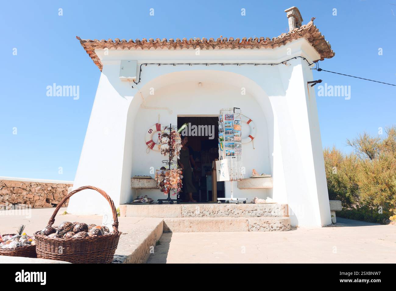 Un affascinante negozio di articoli da regalo sul mare espone cartoline e souvenir della conchiglia sotto il luminoso sole della costa Foto Stock