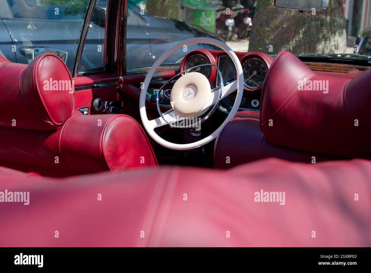 Gli interni in morbida pelle rossa di una Mercedes-Benz d'epoca sono caratterizzati da un classico volante bianco. Foto Stock