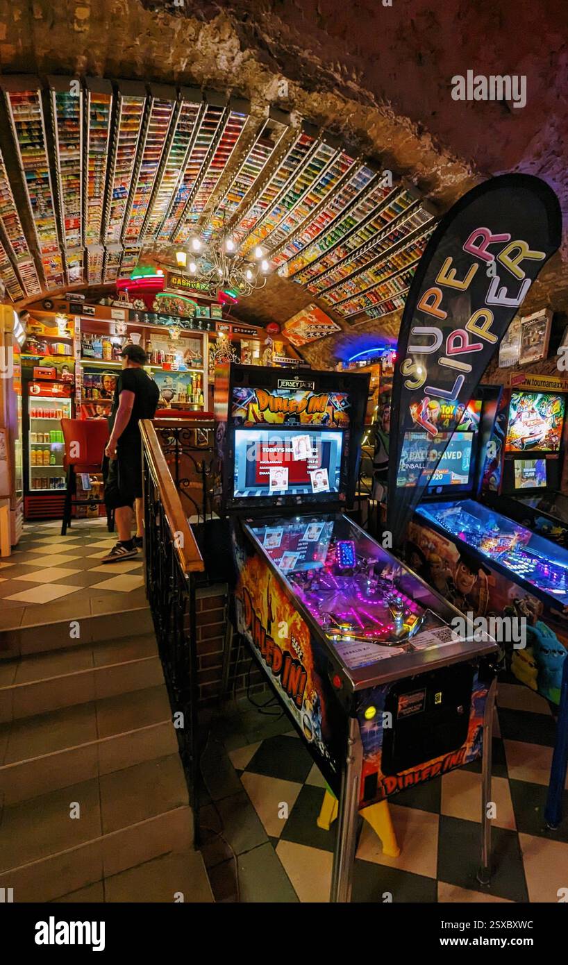 Bar arcade retrò con flipper, arredamento vintage e soffitto unico coperto da oggetti da collezione, creando un'atmosfera da gioco nostalgica. Foto Stock
