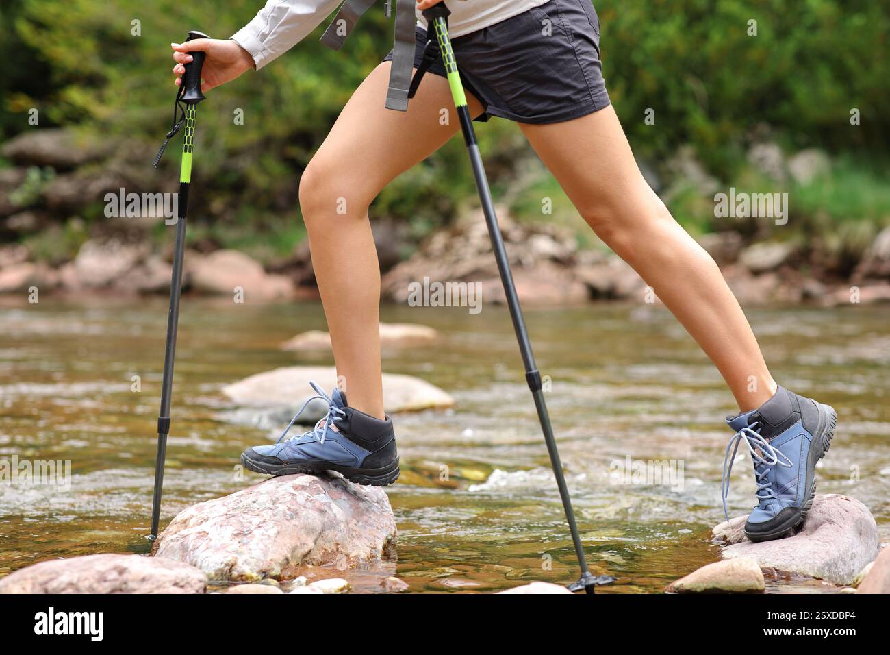 Vista laterale ritratto di una donna che attraversa un fiume di montagna Foto Stock