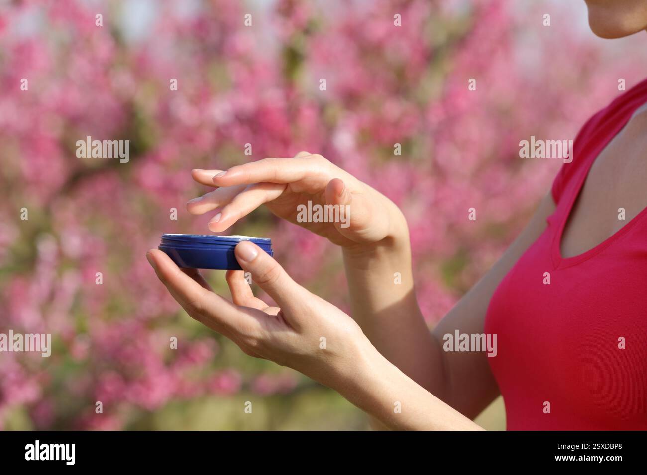 Primo piano di una donna che tiene le mani in mano la crema idratante pronta per essere applicata in un campo Foto Stock