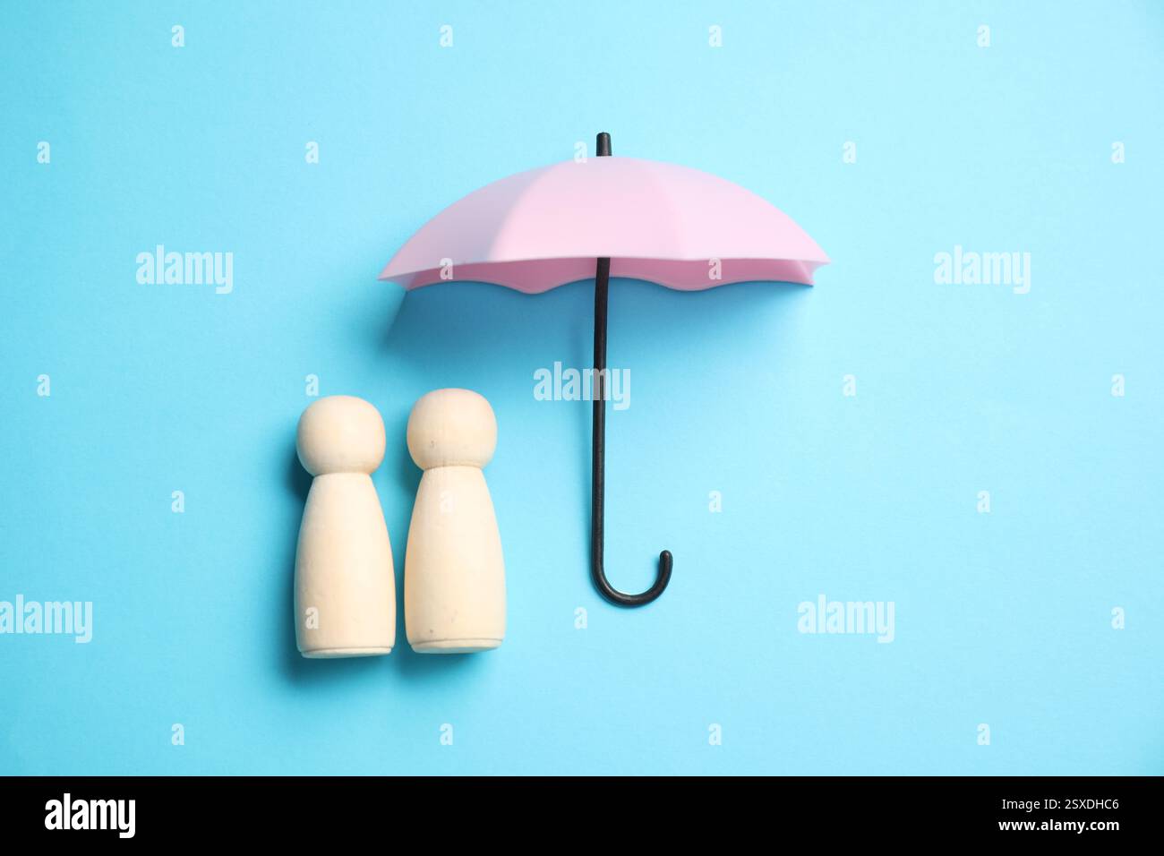 Figure umane sotto l'ombrello su sfondo azzurro, vista dall'alto. Concetto assicurativo Foto Stock