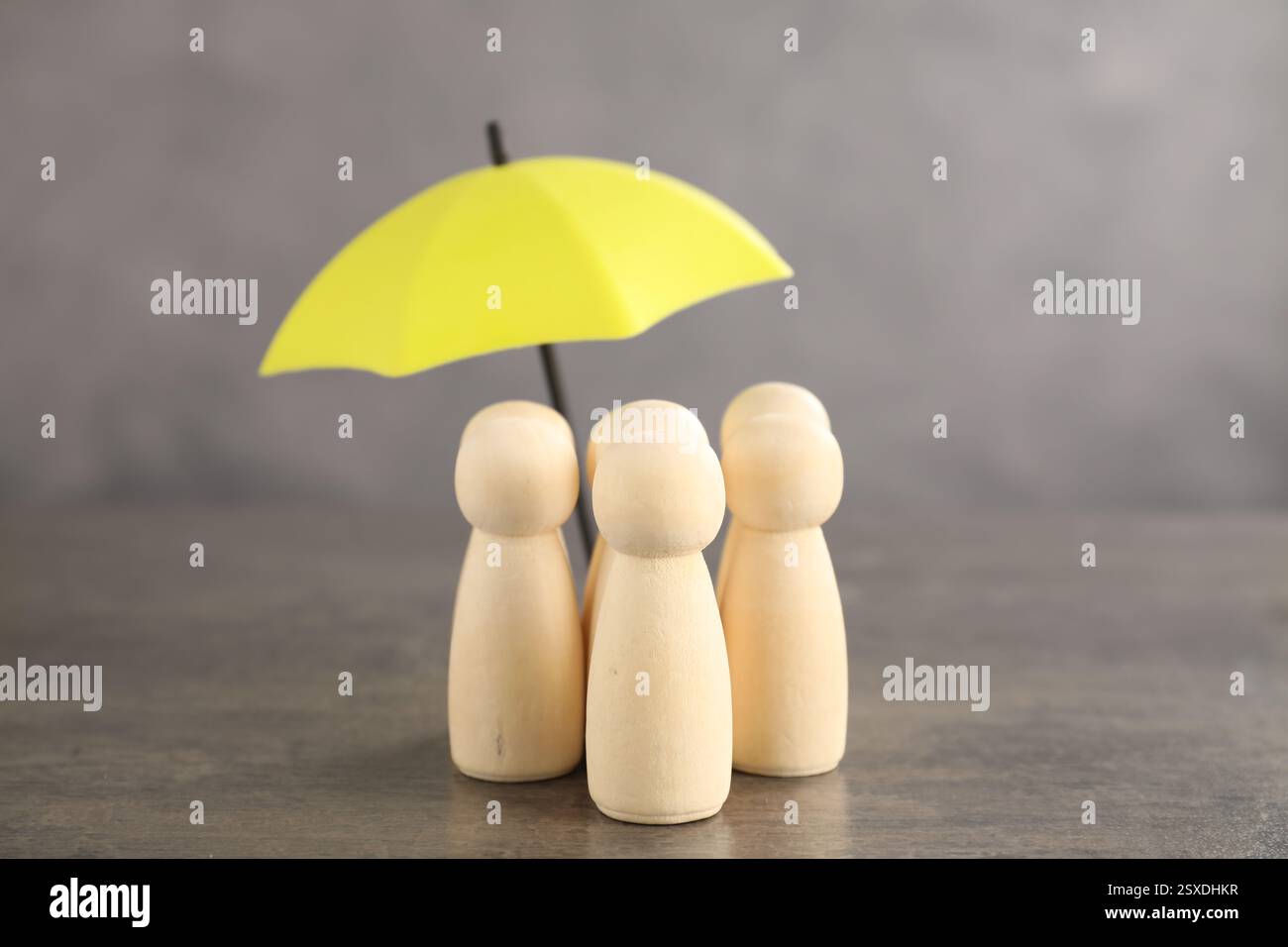 Figure umane sotto l'ombrello sul tavolo grigio. Concetto assicurativo Foto Stock