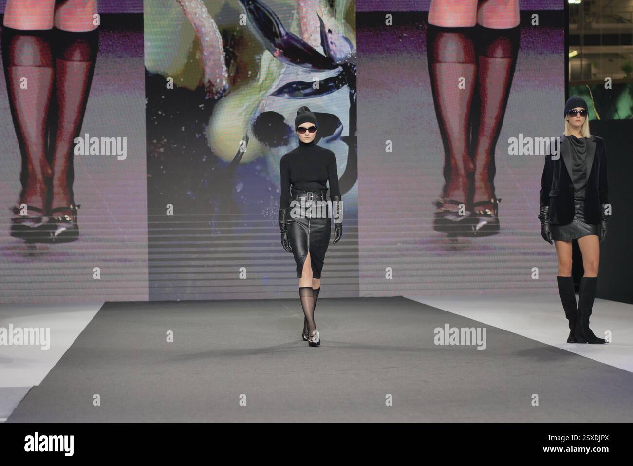 Sfilata Micam: Evento sfilata di moda, con nuove tendenze stilistiche delle calzature abbinate a ginocchiere in nylon nero. Foto Stock