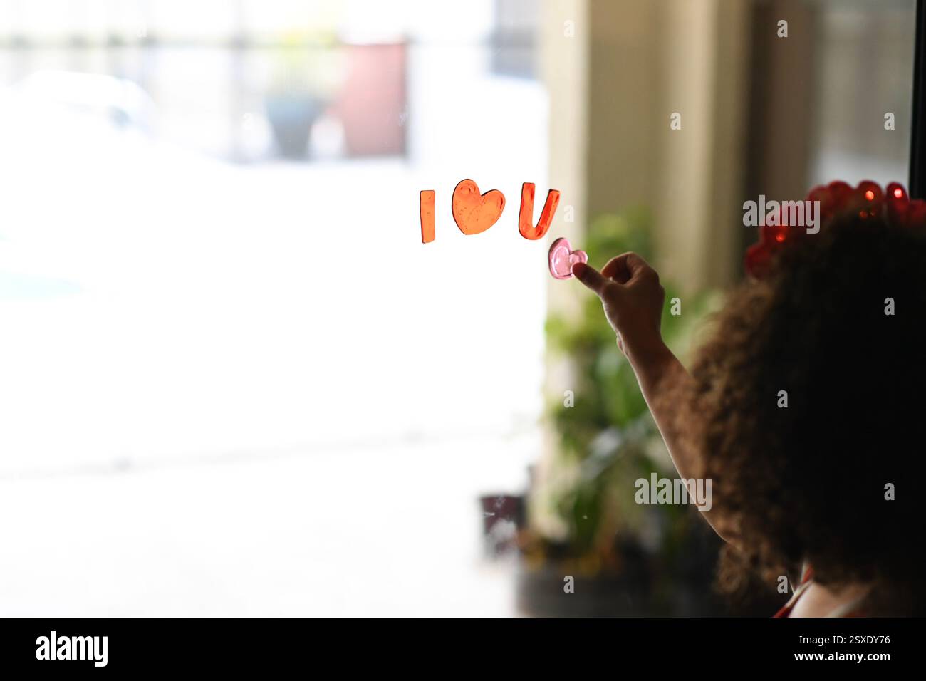 Bambino che posiziona un adesivo a forma di cuore sulla finestra con 'i? Disordine Foto Stock