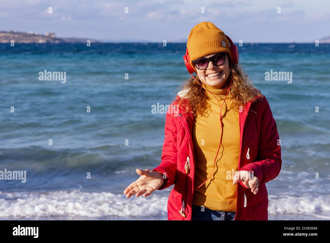 giovane donna con berretto e cuffie che gode di agains ondulato dietro Foto Stock