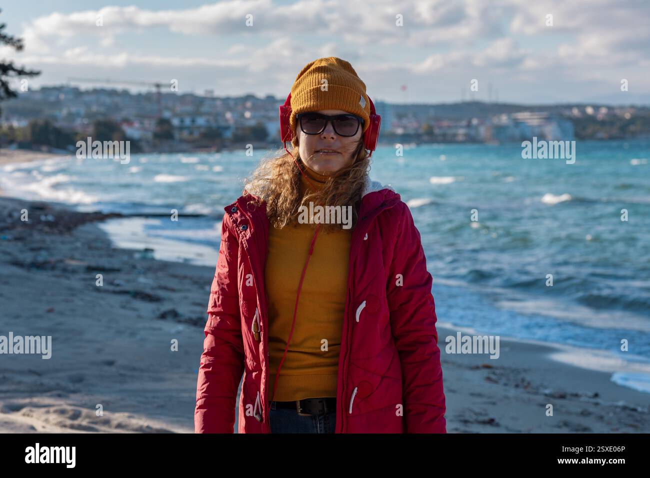 giovane donna con berretto e cuffie che gode di agains ondulato dietro Foto Stock