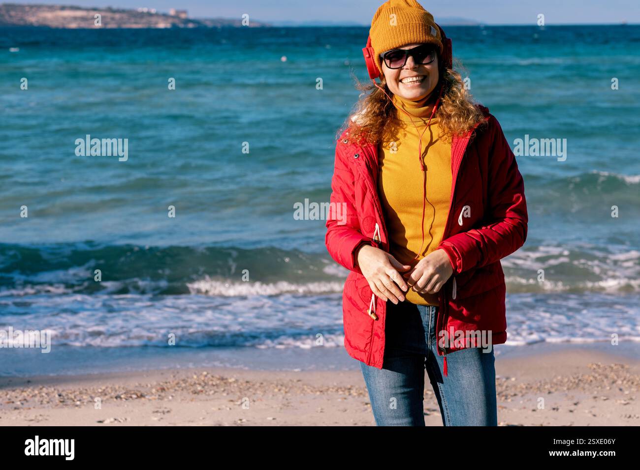 giovane donna con berretto e cuffie che gode di agains ondulato dietro Foto Stock