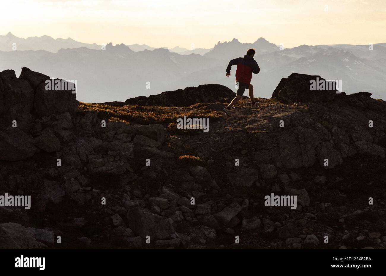 Sagoma al tramonto di un trail runner sul terreno di montagna. Foto Stock