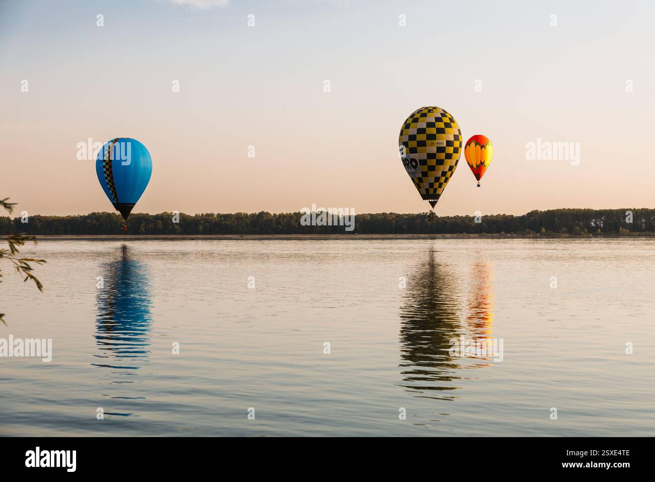 Palloni colorati che volano sopra un lago in una giornata di sole Foto Stock
