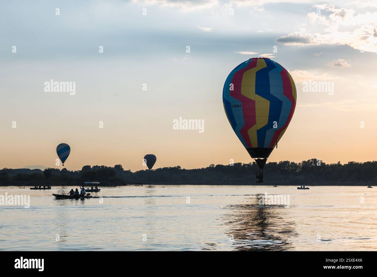 Palloni colorati che volano sopra un lago in una giornata di sole Foto Stock
