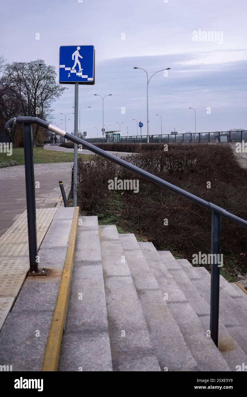 Scala che porta al passaggio pedonale con cartello blu Foto Stock