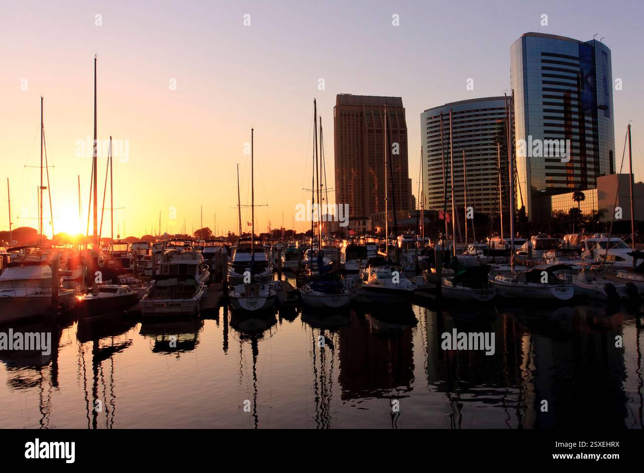 Grande città con un porticciolo pieno di barche. Il sole sta tramontando e l'acqua è calma Foto Stock