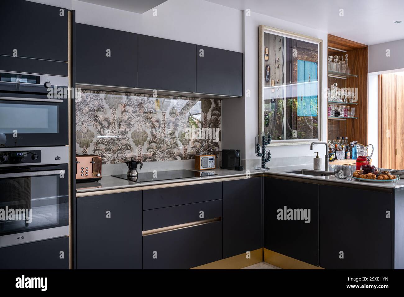 Cucina grigio scuro con splashback Holywood Palm progettato in collaborazione con Annabella Nassetti nella casa di West London. Londra, Regno Unito. Foto Stock