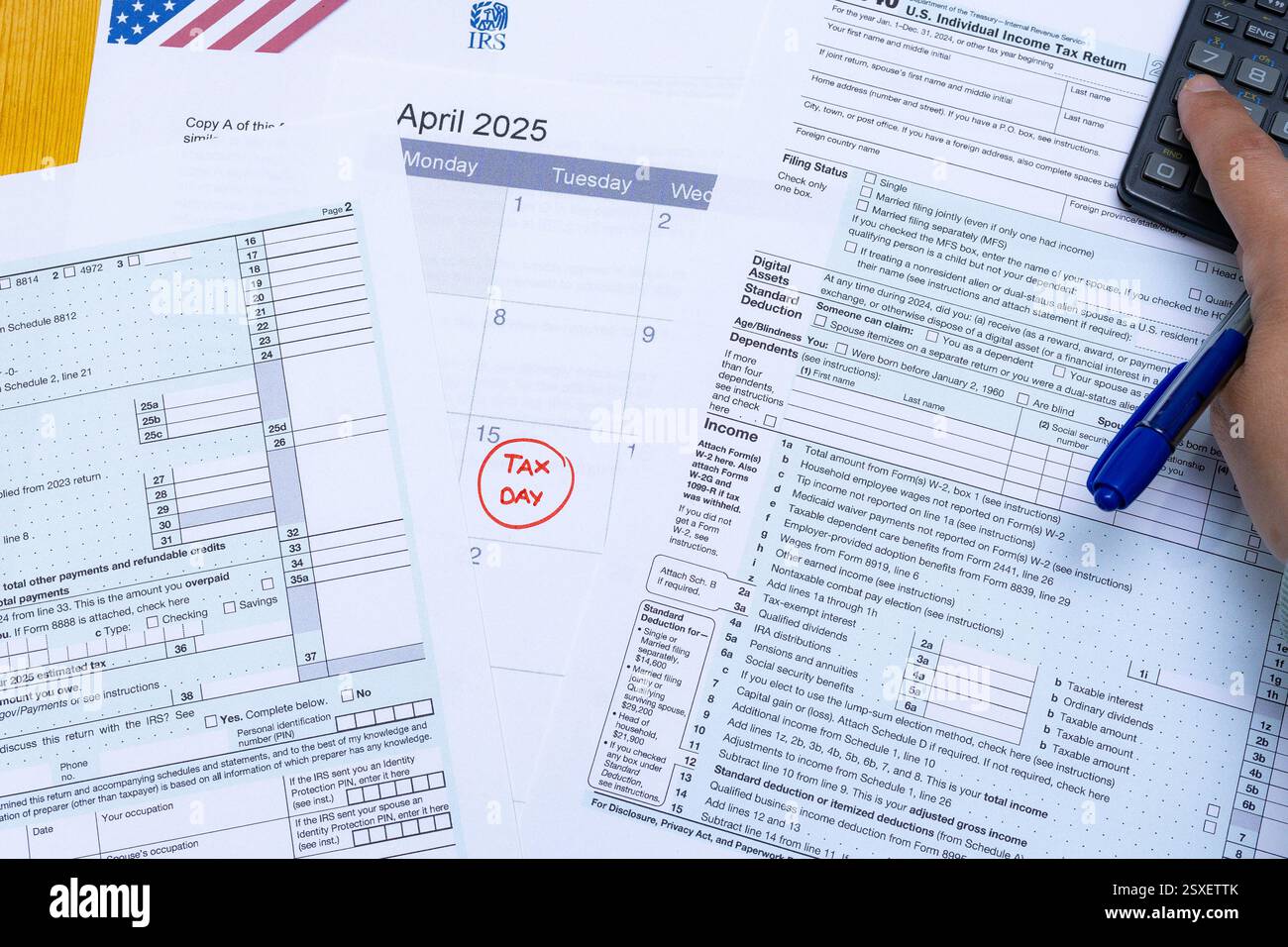 Una raccolta di documenti fiscali statunitensi, incluso il modulo 1040 dell'IRS, distribuiti su una scrivania. Un calendario evidenzia il 15 aprile 2025 come "giorno delle imposte" in rosso. Un ettaro Foto Stock
