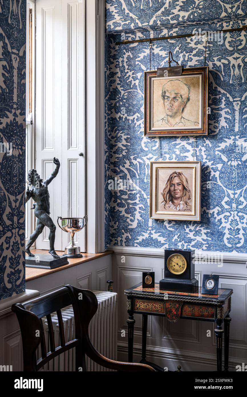 Ritratti di famiglia su carta da parati blu 'Pomegranate Grand' a Bayfield Hall, una storica casa di campagna del XVIII secolo a Norfolk, Regno Unito. Foto Stock