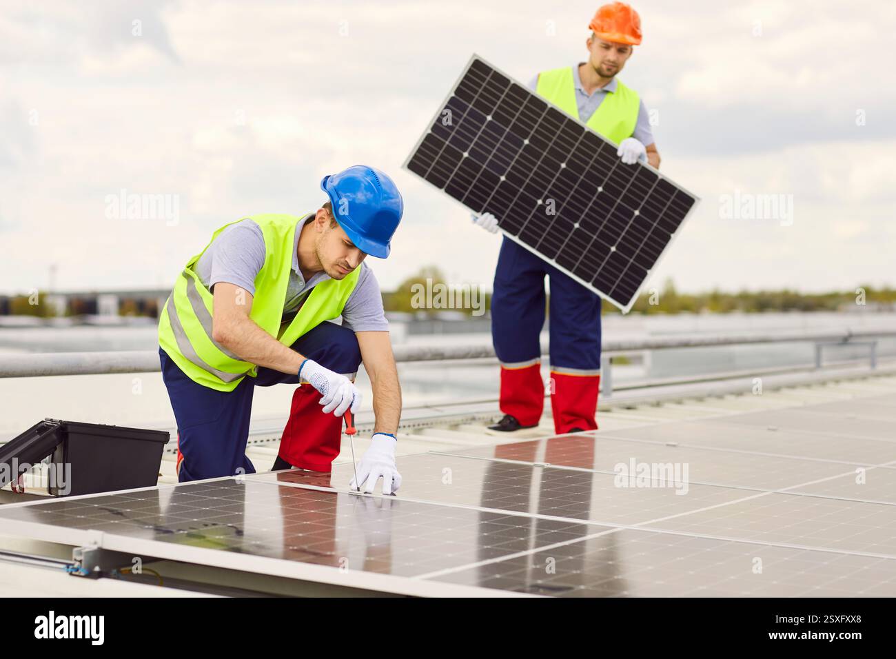Due operai maschi che riparano o installano pannelli solari sul tetto. Foto Stock