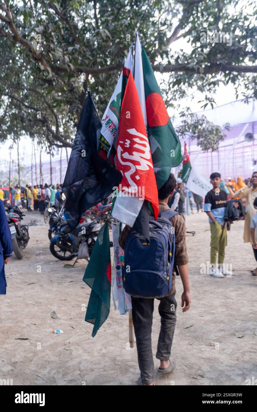 Persona che trasporta più bandiere in un vivace raduno all'aperto con una folla variegata e un'atmosfera festosa Foto Stock