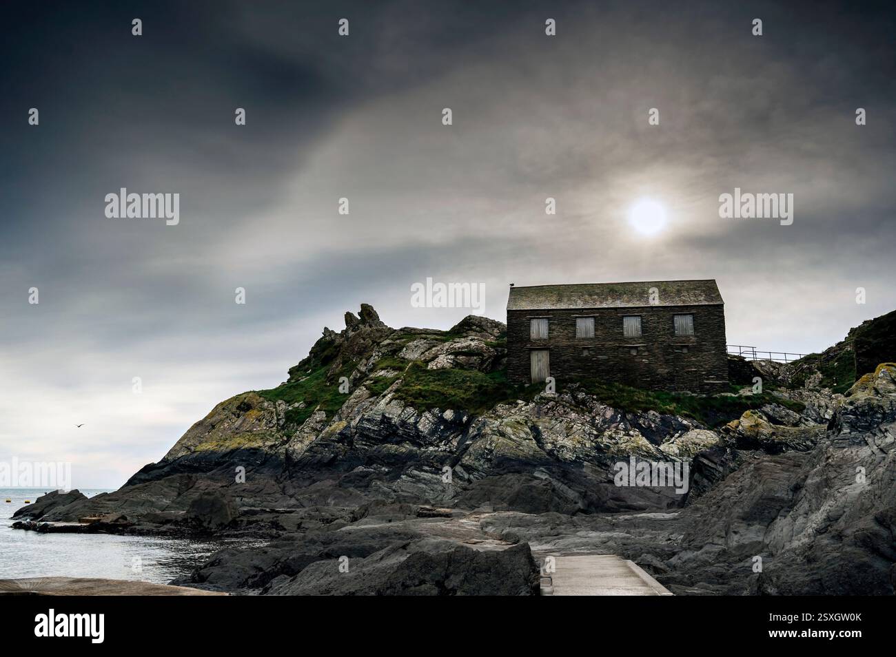 Sun Over Peak Rock & the Net Loft edificio classificato di grado 2, Polperro, Cornwal, Regno Unito Foto Stock