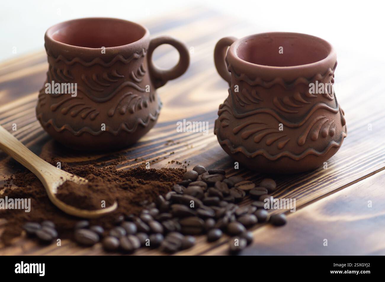Caffè macinato e in grani in un cucchiaio di legno da primo piano e tazza su fondo di legno Foto Stock